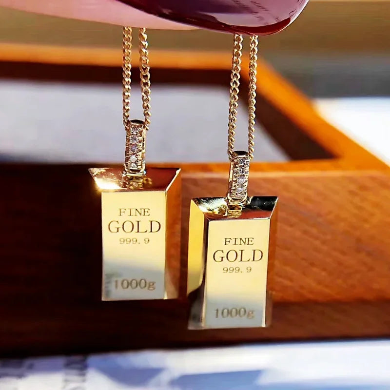 Gold pendants with 'FINE GOLD' text on a wooden surface