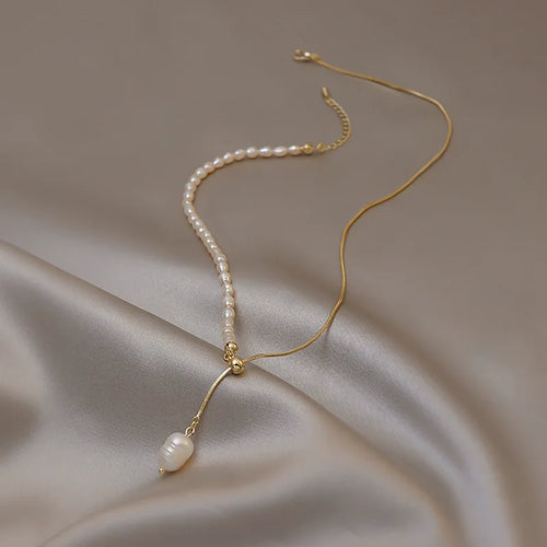 Pearl necklace with 14k gold chain on a beige fabric background